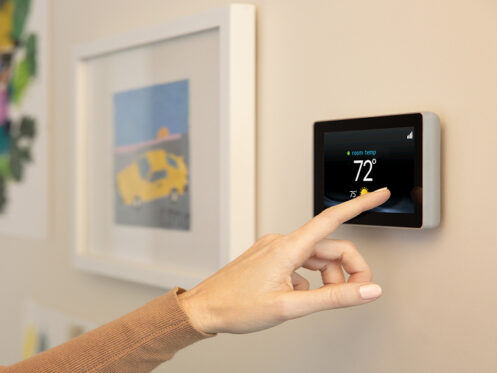 Woman's hand adjusting smart thermostat to 72 degrees