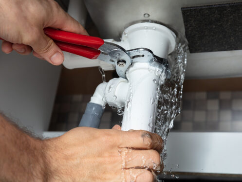 Leaking drain being repaired with a wrench