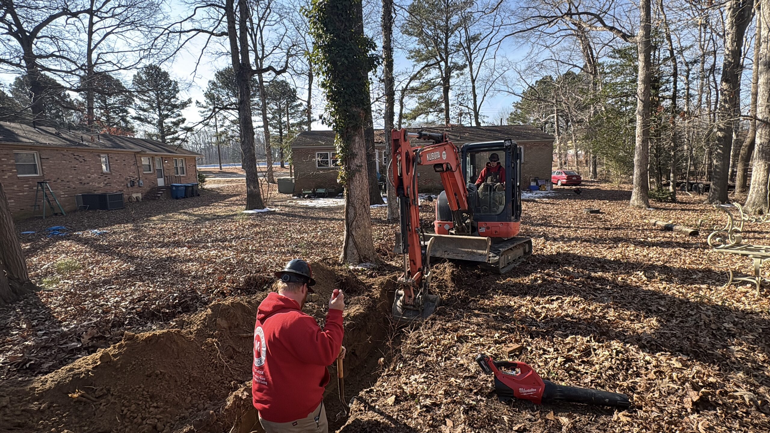 Excavator and trench for sewer line replacement at a home